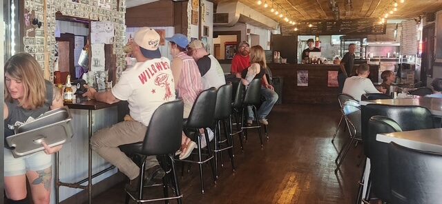 Guests seated at the bar inside The Mad Hatter Saloon, a busy bar in Cascade, CO