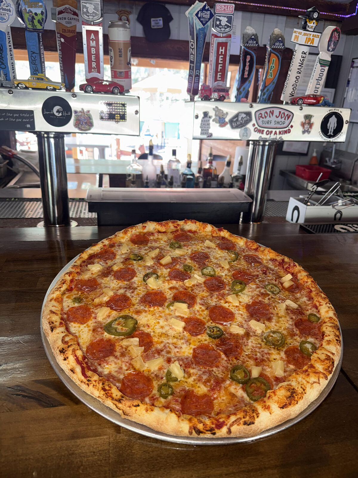 Wood-fired pizza topped with pepperoni, pineapple, and jalapeños at The Mad Hatter Saloon in Cascade, CO